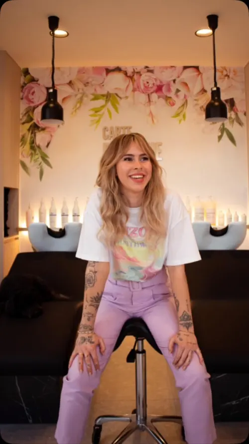 Aukje in het salon van Carte Blanche, met de bloemenwand en de wasbakken achter haar.